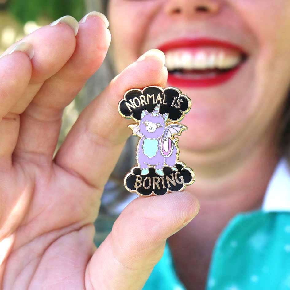 Jubly-Umph_Normal_Is_Boring_Lapel_Pin_between_persons_fingers