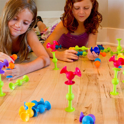 Fat_Brain_Toys_Squigz_Starter_set_girls_lying_on_floor_building_shapes