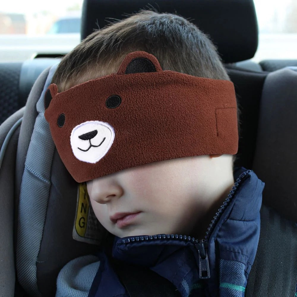 JOEYZ_soft_headphones_bear_in_car . Child wearing a brown bear-shaped eye mask in a car seat