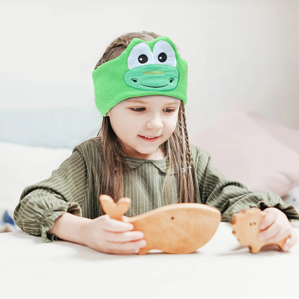 Child wearing a green dino eye mask while holding wooden toys. JOEYZ_soft_headphones_frog_dino_a