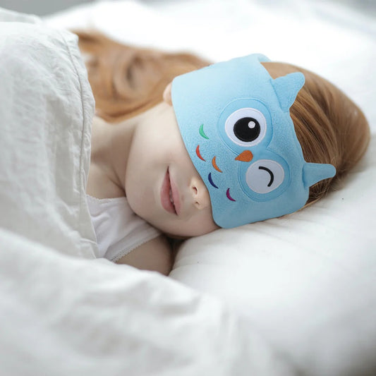 JOEYZ_soft_headphones_sleeping_owl. Child wearing a blue owl-shaped eye mask while lying down.