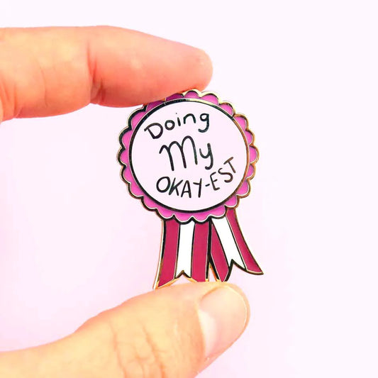 Jubly-Umph_Doing_my_Okayest_lapel_pin_origional_between_persons_fingers