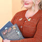 Jubly_Umph_Pin_Books_are_purrfect_lapel_pin_on_ladys_cardigan_lady_is_holding_books