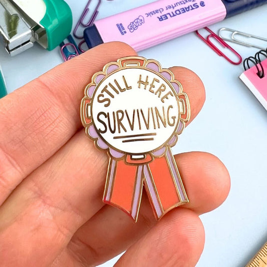 Jubly_Umph_Still_here_surviving_lapel_pin_in_hand