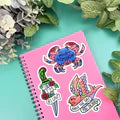 Pink notebook with colorful stickers on a green background