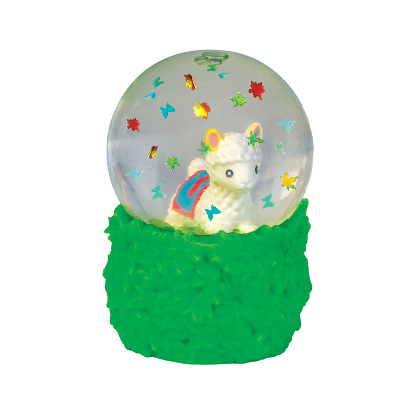 A decorative snow globe figurine with a white llama or alpaca inside a clear globe, surrounded by small colorful star and butterfly decorations, set on a textured bright green base against a plain white background. Smooshos_alpaca_snow_dome_squishiy_close_up
