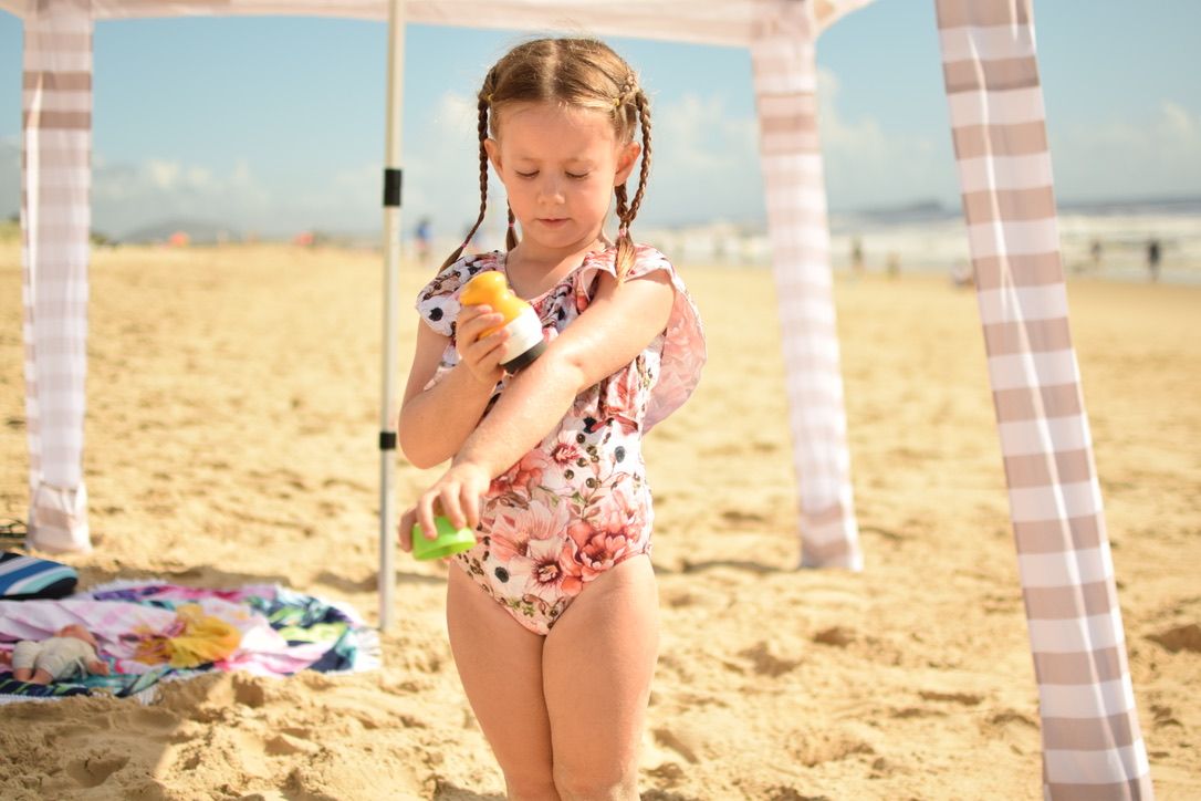 Solar_buddies_child_at_beach_applying_sun_cream_to_her_arm