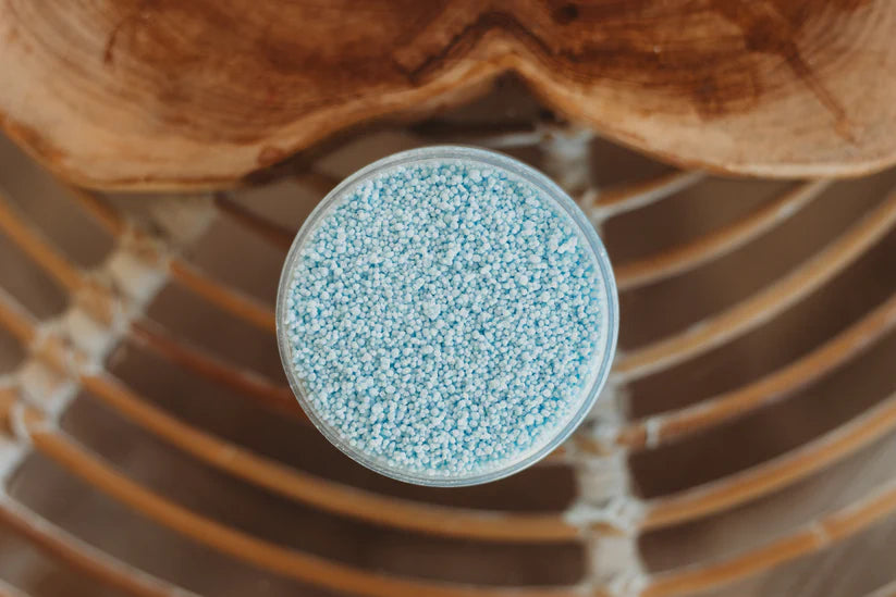 Clear container with blue granules on a wooden surface