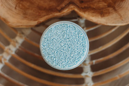 Clear container with blue granules on a wooden surface