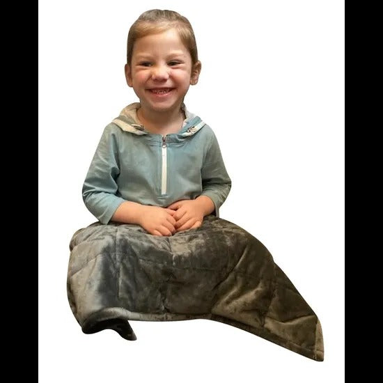 Child wearing a light blue hoodie and dark gray fleece blanket on a white background. Weighted_Lap_Pad_soft_grey_elizabeth_richards_child