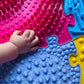Muffik_tinnitots_extra_Large_play_mats_cloase_up_of_childs_hand_and_the_play_mat_textures